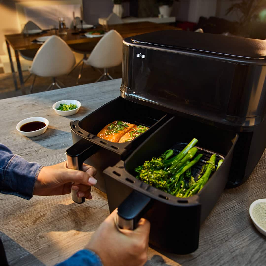 The two drawers of the TwinCook 3 air fryer are pulled out, showing the left drawer filled with freshly grilled fish and the right drawer brimming with perfectly cooked vegetables.